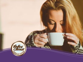 Eine blonde junge Frau hält eine Kaffeetasse.